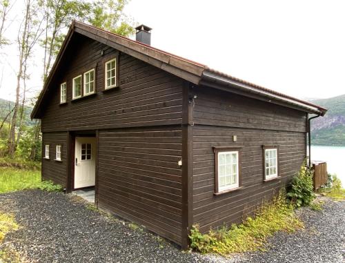 ストリンにあるStryn - Faleide -hytte med fjord og fjell utsiktの白い扉のある小さな茶色の建物