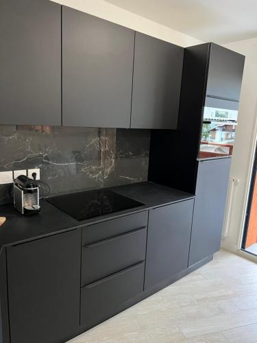 una cocina con encimeras negras y armarios blancos en Superbe studio a Auron avec terrasse plein sud, en Auron