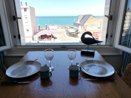 a table with two empty glasses and a view of the ocean at L'HORIZON Vue mer et falaises in Fécamp