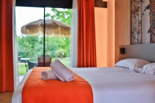 a room with a bed with a towel on it at Logis Hôtel & Spa Déjeunez Sous L'Arbre in Rousset