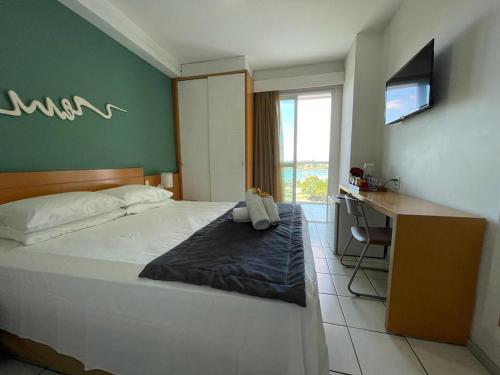 Schlafzimmer mit einem Bett, einem Schreibtisch und einem TV in der Unterkunft Thuis I Studio Espetacular na Praia do Canto in Vitória