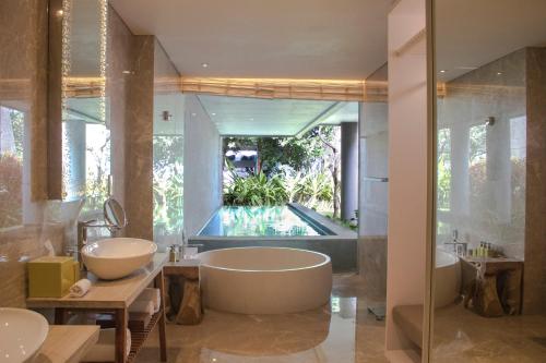 a bathroom with a tub and a bathtub in it at Maya Sanur Resort & Spa in Sanur