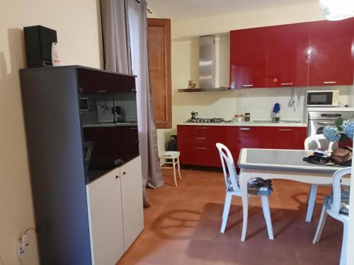 CoccorinoにあるCapo Vaticano 7km Casa vacanze in Monte Poroのキッチン(赤いキャビネット、テーブル、椅子付)