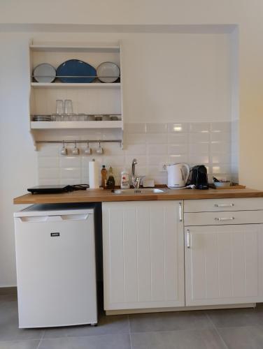 a kitchen with white cabinets and a white refrigerator at Κallisto rooms in Mytakas