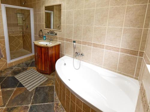 a bathroom with a tub and a shower and a sink at Golf & Tides in Mossel Bay
