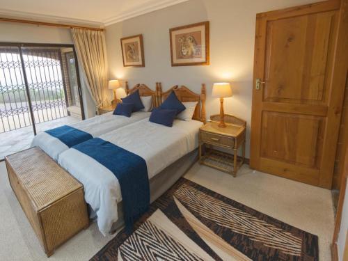 a bedroom with a large bed with blue pillows at Golf & Tides in Mossel Bay