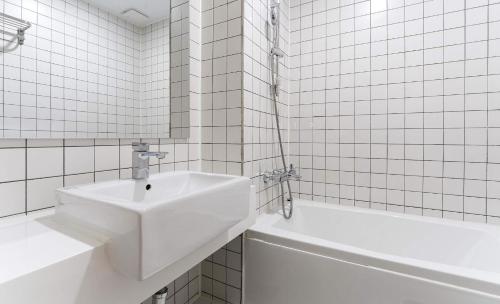 a white bathroom with a sink and a bath tub at H Avenue Hotel Idae Shinchon in Seoul