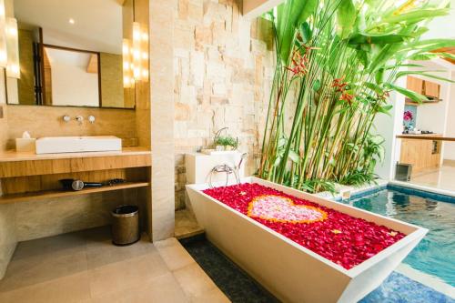 La salle de bains est pourvue d'une baignoire remplie de fleurs rouges. dans l'établissement The Mavila - CHSE Certified, à anur