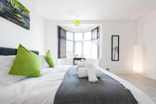 a white bedroom with a large bed with green pillows at Jasmine Villa B - Ideal for QMC & Uni - Free parking in Nottingham