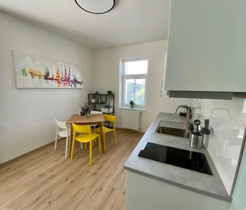 a kitchen and dining room with a table and yellow chairs at Berta's Apartments in Děčín