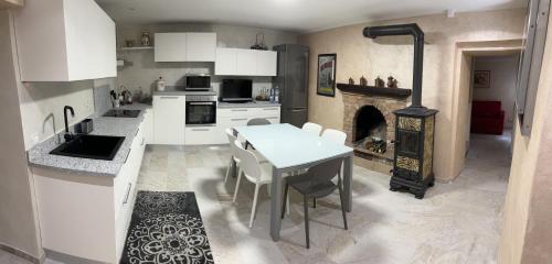 a kitchen with white cabinets and a table and a fireplace at IL NIDO DELLA POIANA CASA VACANZE e B & B in Montalto Pavese