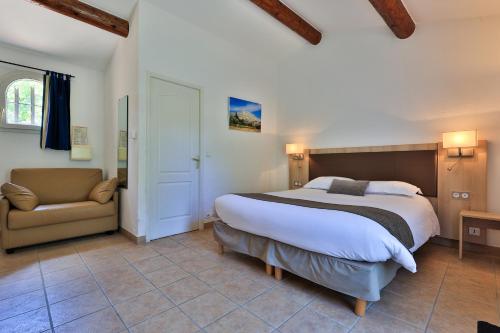 a bedroom with a large bed and a chair at Logis Hôtel & Spa Déjeunez Sous L'Arbre in Rousset