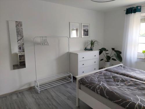 a white bedroom with a bed and a dresser at Gemütliches, voll ausgestattetes Apartment in Halle an der Saale