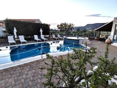 a swimming pool with white chairs and a building at Taletos Apartments in Stoupa