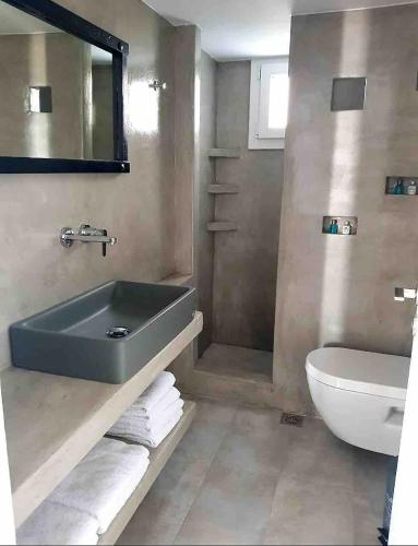 a bathroom with a tub and a toilet and a sink at BLUE WATERS MYKONOS in Ornos