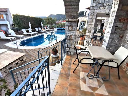 a balcony with a table and chairs and a pool at Taletos Apartments in Stoupa