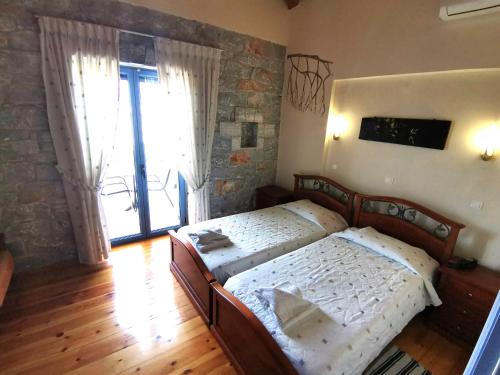 a bedroom with two beds and a large window at Taletos Apartments in Stoupa