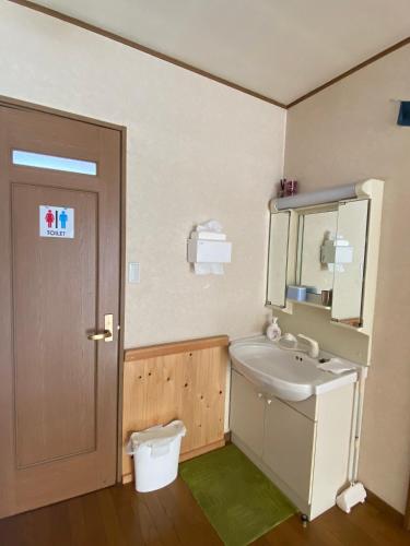 a bathroom with a sink and a mirror and a toilet at Azumino Backpackers 山の風 in Matsukawa