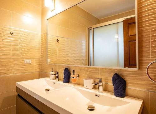 a bathroom with a sink and a large mirror at Airport View 3-Bed Villa in Cupecoy