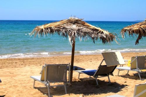 a group of chairs and an umbrella on the beach at Cala San Giorgio Residence in Sciacca