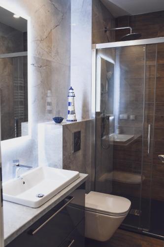 a bathroom with a sink and a toilet and a shower at Apartamenty Wrzosowa in Dębki