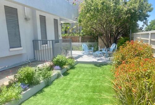 a garden with chairs and flowers in a yard at אירוח השקד - 10דק' משדה התעופה in Giv‘at Koaẖ