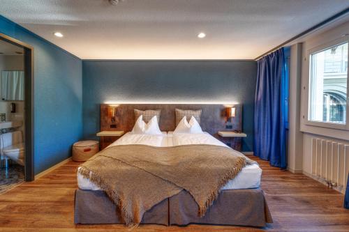 a bedroom with a large bed with blue walls at The HEY HOTEL in Interlaken