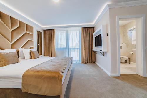 a hotel room with a large bed and a television at 3 Stejari Brasov in Braşov