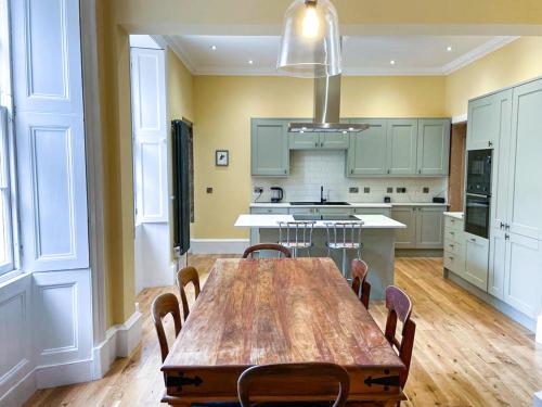 a large kitchen with a wooden table and chairs at Remarkable 5BR Townhouse with Garden, Sleeps 12 in Edinburgh