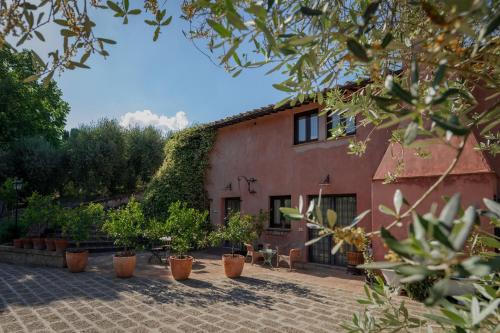a red building with potted plants in front of it at Borgodoro - Natural Luxury Bio Farm in Magliano Sabina