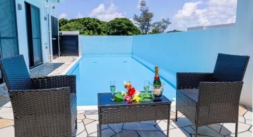 een zwembad met twee stoelen en een tafel met bloemen erop bij Private Pool Villa Motobu in Motobu