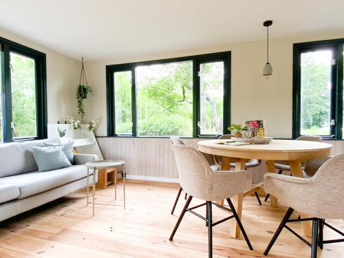 ein Wohnzimmer mit einem Tisch, Stühlen und einem Sofa in der Unterkunft Idyllic house with 360 view of nature in Dalfsen