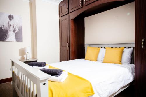 um quarto com uma cama grande e almofadas amarelas em Rigside House em Douglas