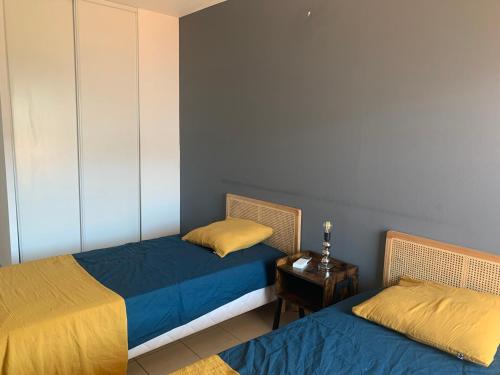 een kamer met 2 bedden en een tafel met een bijzettafel bij Bel appartement neuf climatisé & parking in Perpignan