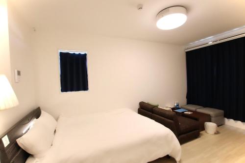 pokój hotelowy z łóżkiem i kanapą w obiekcie Hotel Southern Suite Kugai w mieście Miyako-jima
