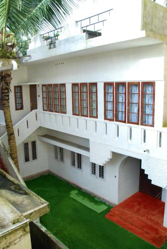 a white house with a green lawn in front of it at Jojies Homestay Fortkochi in Cochin