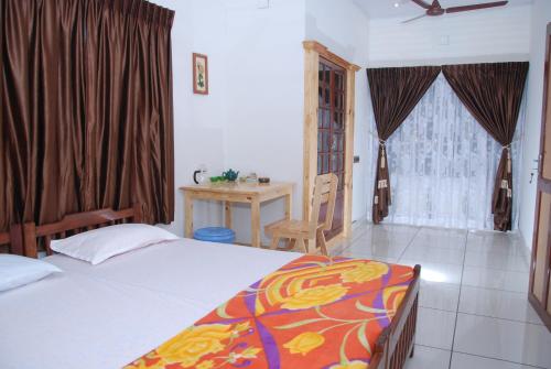 a bedroom with a bed and a table and a window at Jojies Homestay Fortkochi in Cochin