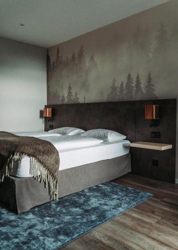 a bedroom with a large bed with a painting on the wall at The HEY HOTEL in Interlaken
