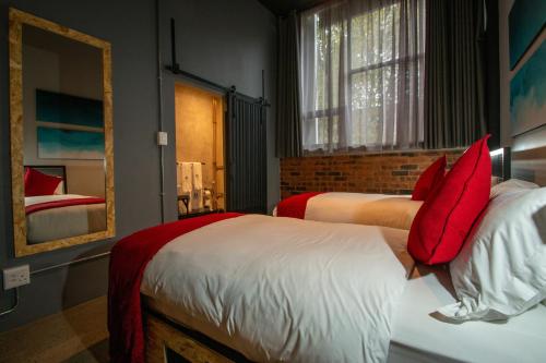 a bedroom with two beds with red pillows and a mirror at Lilian Lofts Hotel & Spa in Johannesburg