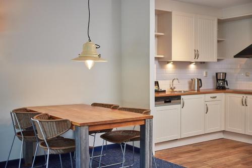 a kitchen with a wooden table and chairs at WestCord ApartHotel Boschrijck in West-Terschelling