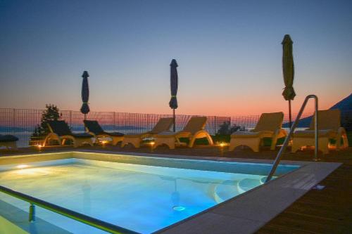 a swimming pool with chairs and a sunset in the background at Pantheon Hotel & Suites in Nerotriviá