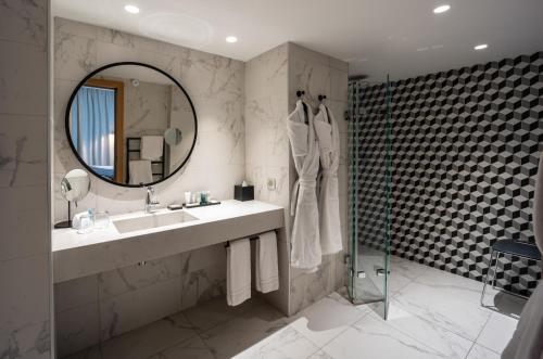 a bathroom with a sink and a mirror and a shower at Thalazur Saint Jean de Luz - Hôtel & Spa in Saint-Jean-de-Luz