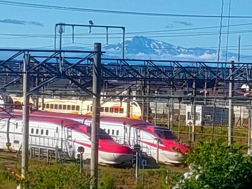 two trains on the tracks with mountains in the background at Apartment House Akita in Akita