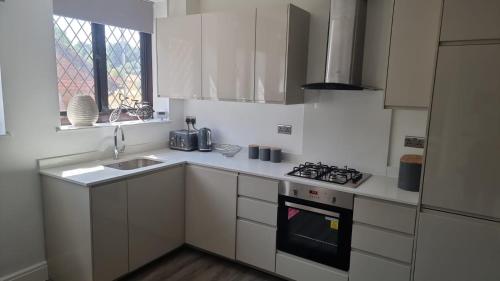 a white kitchen with a sink and a stove at Jasmin Apartments - Luxury 1 & 2 Bedroom units with Free Parking in Bushey