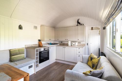uma cozinha com armários brancos e um sofá num quarto em Shepherds View at Oaks Barn Farm Alcester with optional paid for Hot tub 