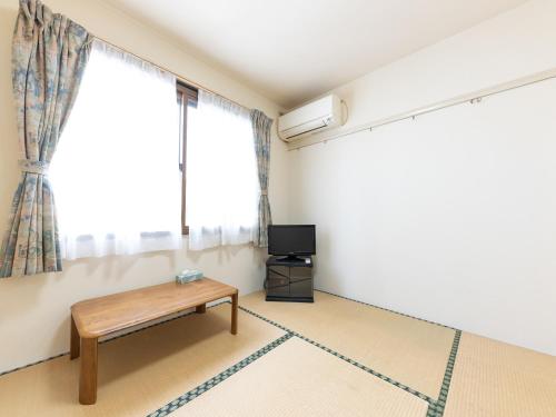 a living room with a table and a tv at Ryosou Minatosou Joetsu in Naoetsu