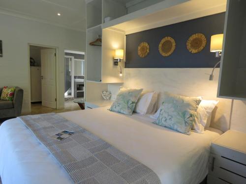 a bedroom with a large white bed with blue pillows at Bare Feet Retreat in Scottburgh