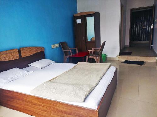 a bedroom with a bed and chairs in a room at STAYMAKER Pushpagiri Comforts in Sakleshpur