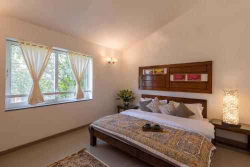 une chambre avec un grand lit et deux fenêtres dans l'établissement El Cottage by StayVista - An enchanting escape with Scenic views, Colonial decor & Private plunge pool, à Lonavala