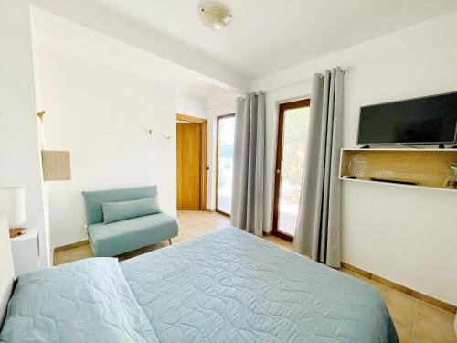 sypialnia z łóżkiem, telewizorem i krzesłem w obiekcie Profumo di Limoni Vacation Rental w mieście Procida